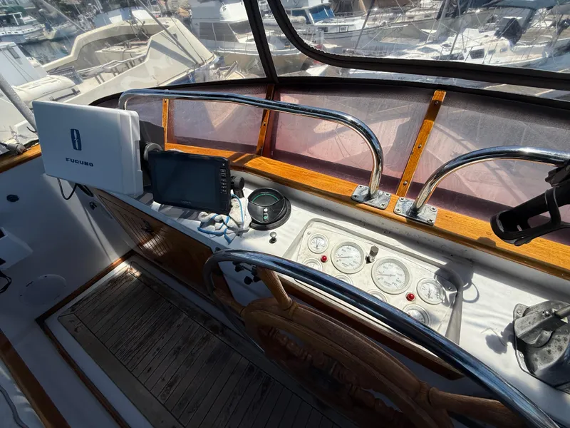 1981 DeFever Passagemaker helm with navigation equipment and gauges in a marina setting.