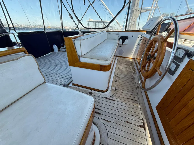 1981 DeFever Passagemaker helm with wooden wheel and cushioned seating.