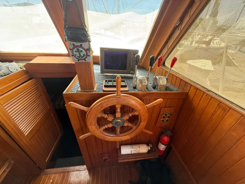 1981 DeFever Passagemaker helm with wooden wheel, navigation equipment, and control levers.