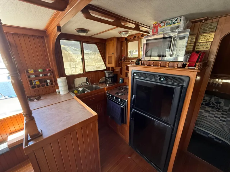 1981 DeFever Passagemaker yacht kitchen with wood cabinetry, appliances, and cozy interior.