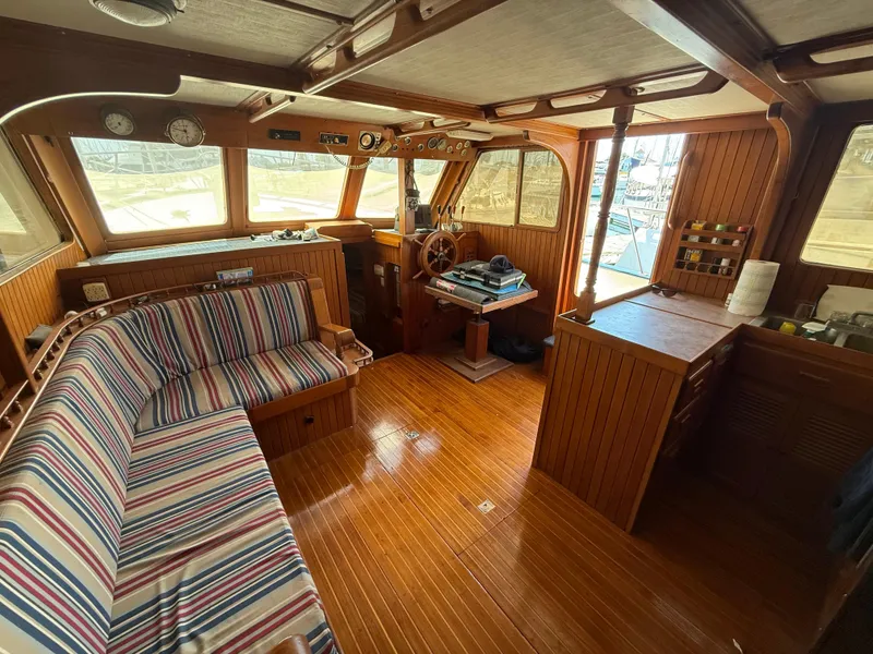1981 DeFever Passagemaker interior with striped seating, wooden helm, and nautical decor.