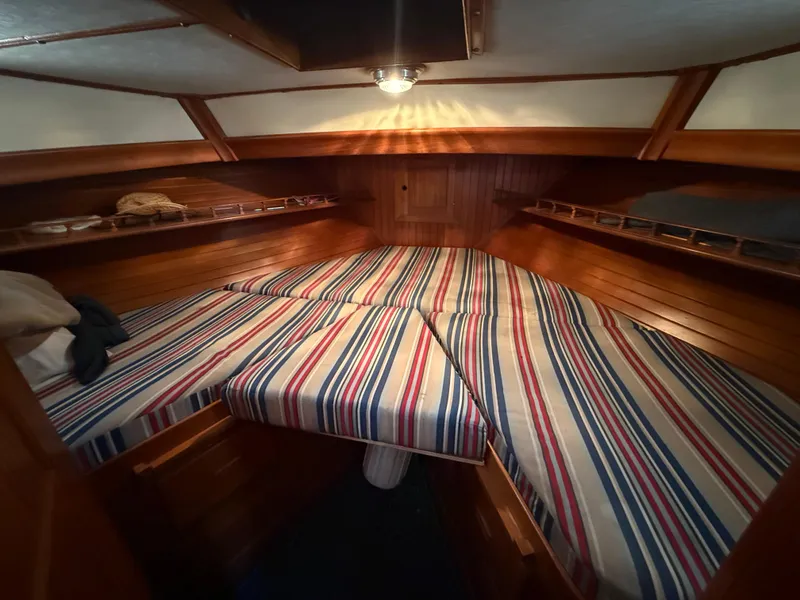 1981 DeFever Passagemaker cabin with striped bedding and wooden interior.