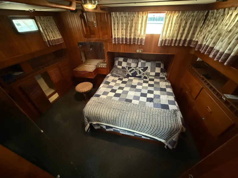 1981 DeFever Passagemaker cabin with wood paneling, bed, and nautical decor.