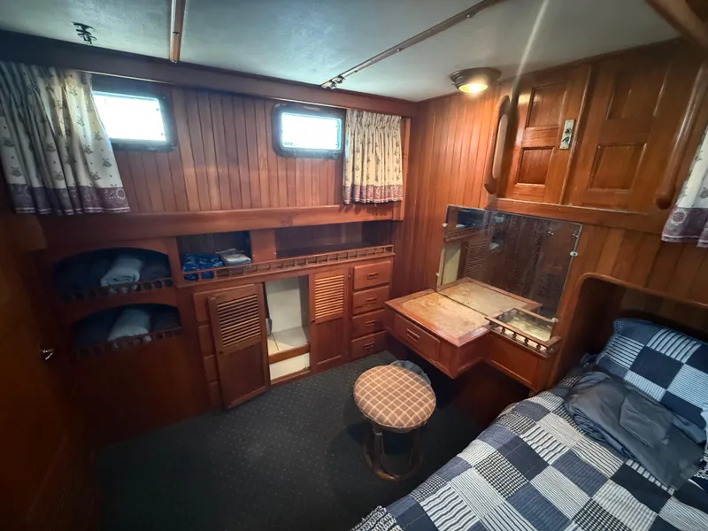 1981 DeFever Passagemaker cabin with wood paneling, bed, and storage. Cozy nautical interior.