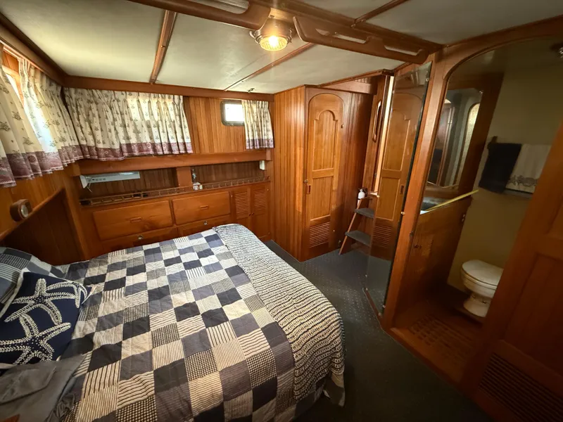 Cozy cabin interior of 1981 DeFever Passagemaker with wood paneling and nautical decor.
