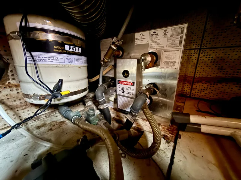 Engine room of 1981 DeFever Passagemaker with pressure storage tank and high voltage warning.