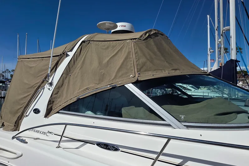 2002 Sea Ray 340 Sundancer boat with tan canvas cover in marina.