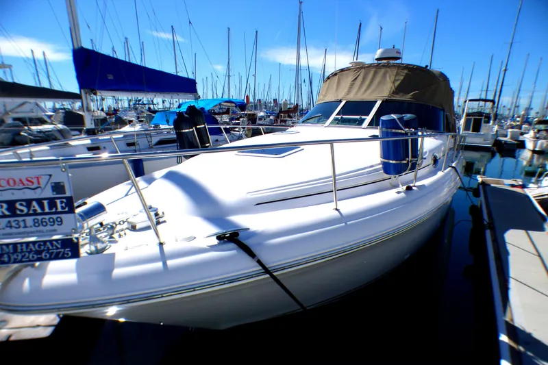 2002 Sea Ray 340 Sundancer yacht docked, for sale, in a marina under clear blue skies.