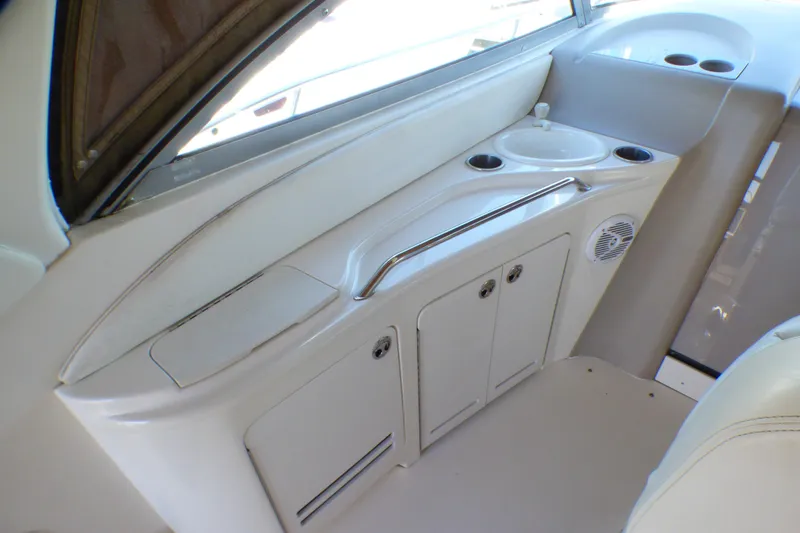 2002 Sea Ray 340 Sundancer interior with sink, storage, and cup holders.