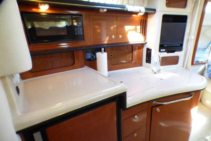 2002 Sea Ray 340 Sundancer yacht kitchen with microwave, sink, and wooden cabinetry.