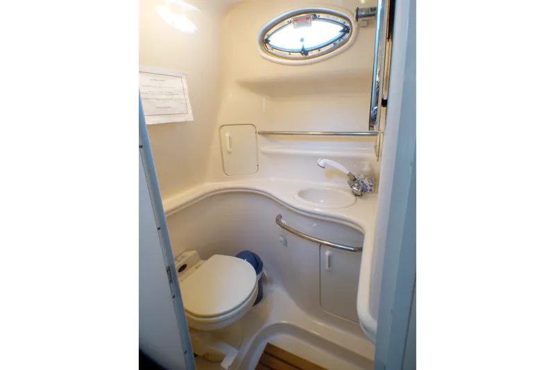 2002 Sea Ray 340 Sundancer bathroom with toilet, sink, and porthole window.