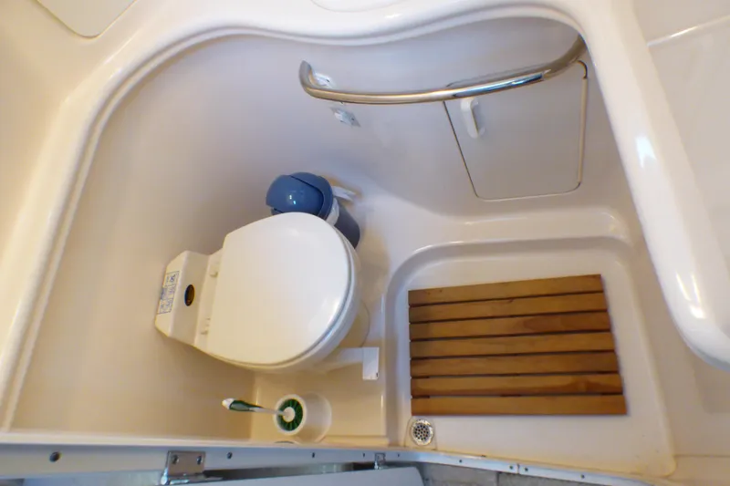 Bathroom of 2002 Sea Ray 340 Sundancer with toilet and wooden floor mat.