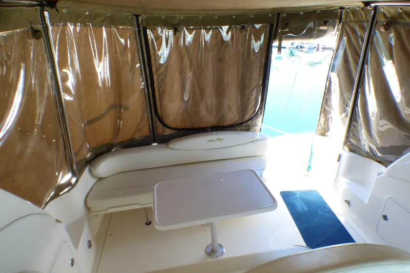 2002 Sea Ray 340 Sundancer interior with seating and table, enclosed by clear curtains.