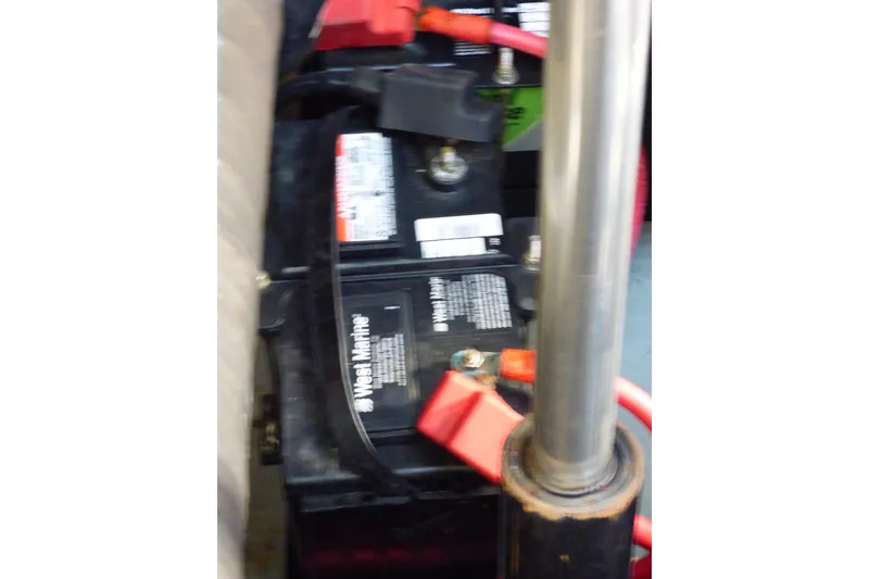 Battery compartment of 2002 Sea Ray 340 Sundancer with red cables and marine battery.