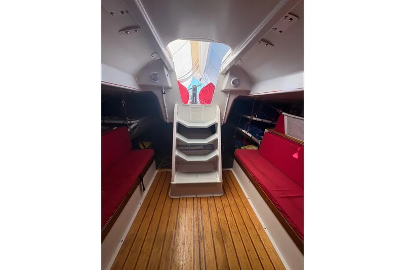 Interior of 1999 Laurie Davidson TP-52 sailboat with red seating and wooden flooring.
