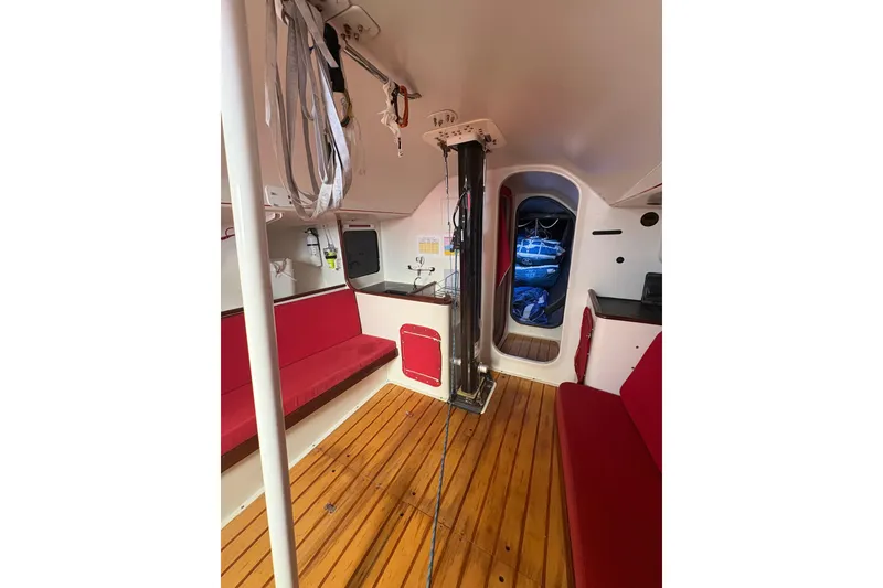 Interior of 1999 Laurie Davidson TP-52 yacht with red seating and wooden flooring.