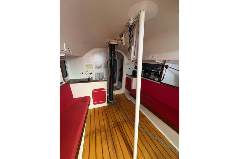 Interior of 1999 Laurie Davidson TP-52 yacht with red seating and wooden flooring.