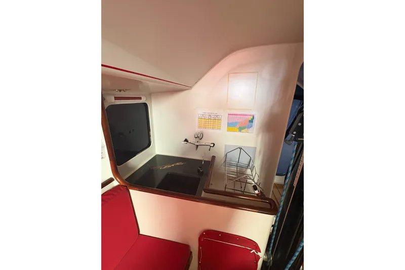 Interior of 1999 Laurie Davidson TP-52 yacht with red seating and navigation charts.