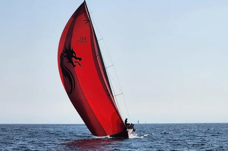 Red sailboat on open sea, Laurie Davidson TP-52, 1999 model, with dragon design.