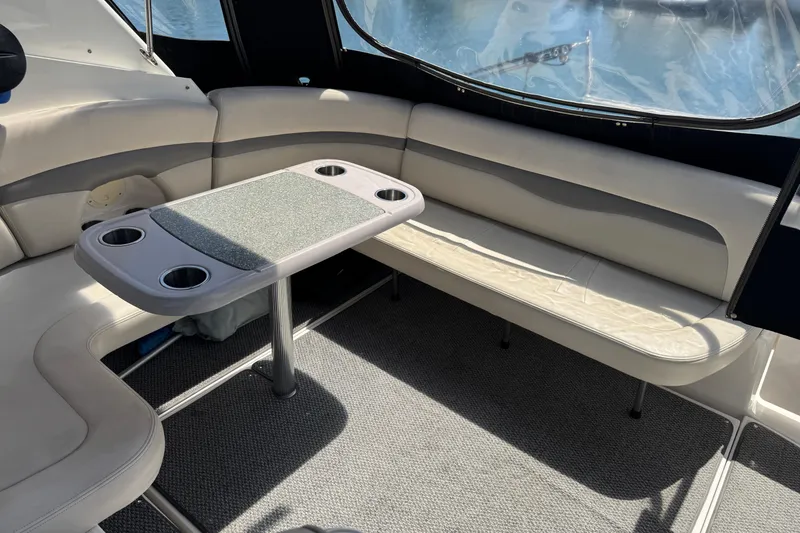 Interior seating area of 2006 Chaparral Signature 350 boat with table and cup holders.