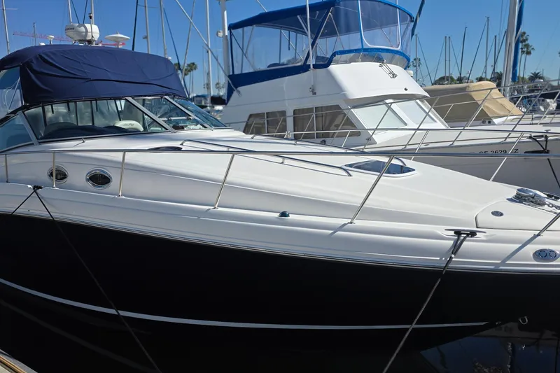 2005 Sea Ray 340 Sundancer yacht docked at marina, featuring sleek design and blue canopy.