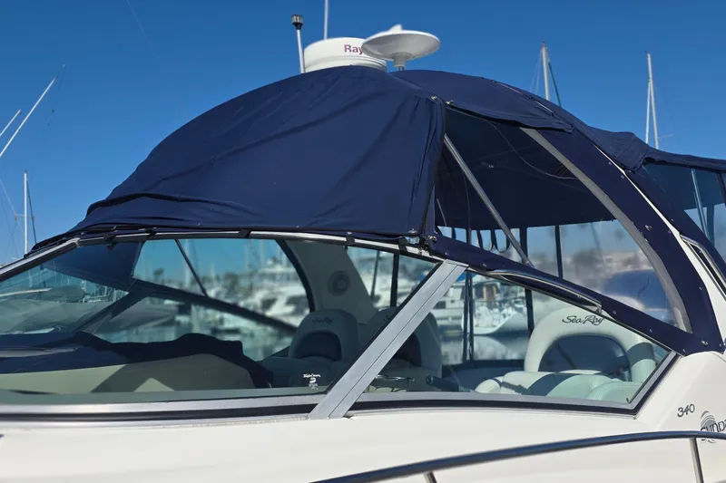 2005 Sea Ray 340 Sundancer boat with blue canopy in marina setting.