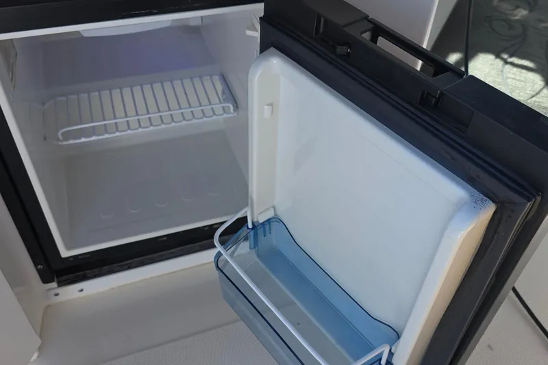 Open refrigerator on 2005 Sea Ray 340 Sundancer boat, showing interior shelves and door storage.