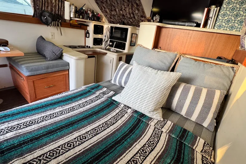 Interior of 1998 Luhrs Tournament 320 Convertible with cozy bedding and compact kitchen area.