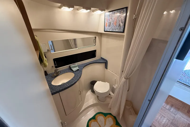 Bathroom interior of 1998 Luhrs Tournament 320 Convertible yacht, featuring sink, toilet, and mirror.