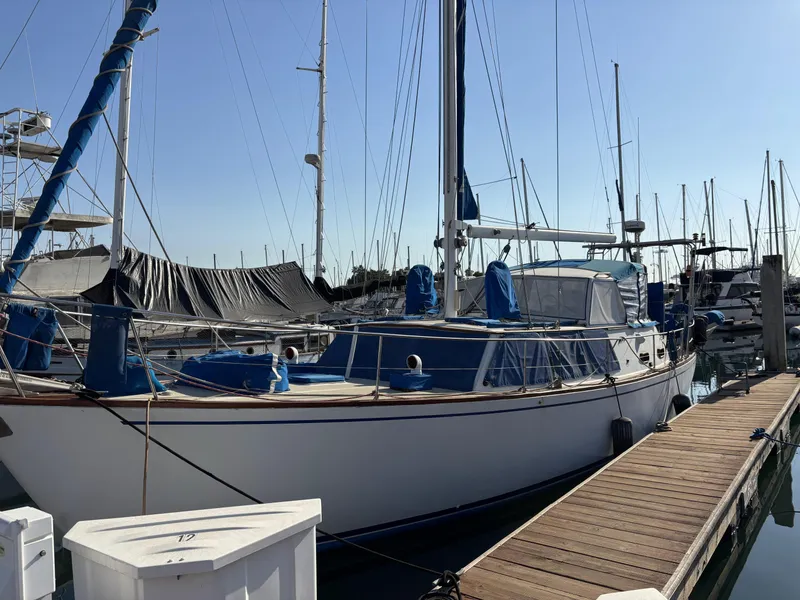 1973 CAL 246 sailboat docked at marina, featuring blue accents and clear sky background.
