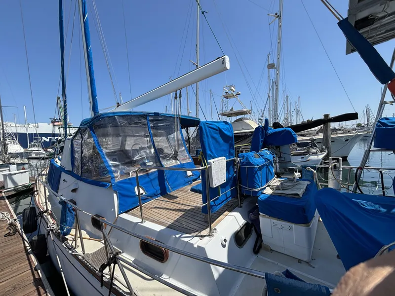 Sailboat docked at marina, CAL 246 model, 1973, with blue covers and clear skies.