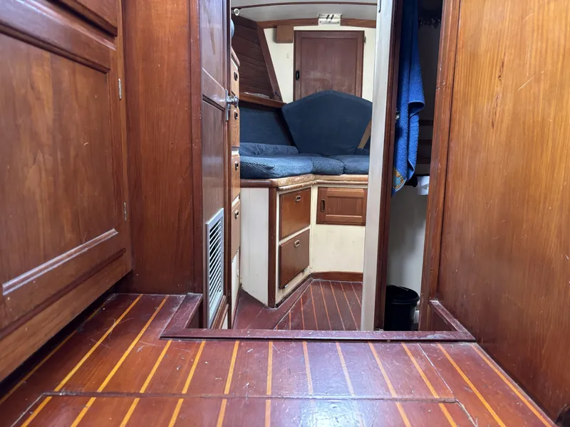 Interior of a 1973 CAL 246 sailboat with wooden cabinetry and flooring.