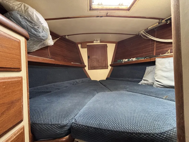 1973 CAL 246 sailboat interior with blue cushions and wooden cabinetry.