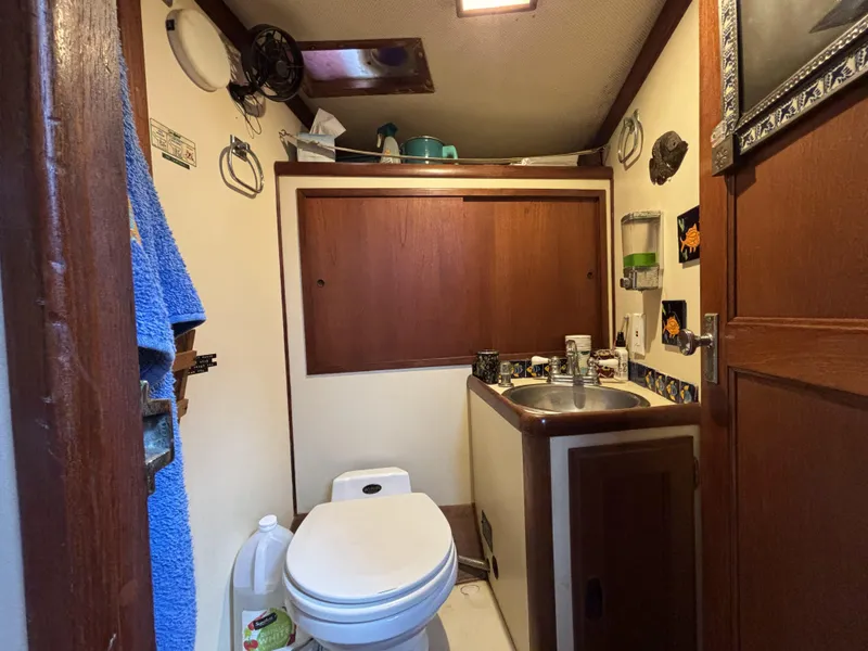 Small boat bathroom with toilet, sink, and wooden cabinetry, CAL 246, 1973 model.