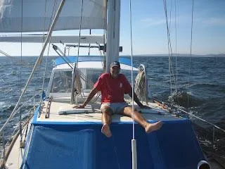 Man relaxing on 1973 CAL 246 sailboat deck, sailing on open sea.