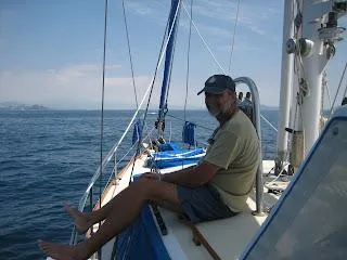 Man relaxing on a 1973 CAL 246 sailboat at sea.