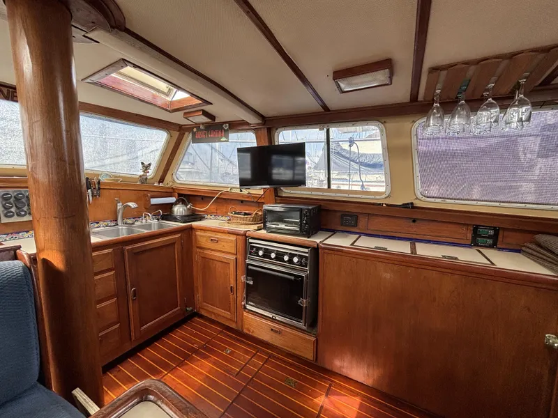 1973 CAL 246 yacht interior with wooden cabinetry, stove, and windows.