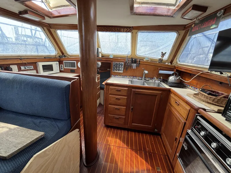 1973 CAL 246 yacht interior with wooden cabinetry, kitchen, and seating area.