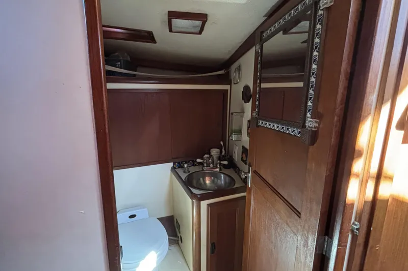 1973 CAL 246 boat bathroom with sink, toilet, and wooden cabinetry.