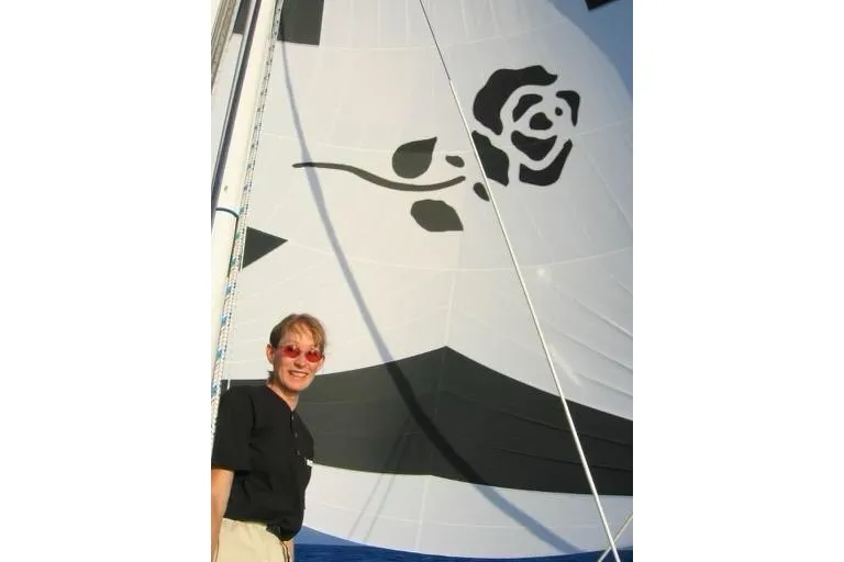 Person smiling on a CAL 246 sailboat with a rose design on the sail, 1973 model.