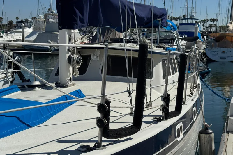 1988 Gulf Pilot House sailboat docked in a marina, featuring blue covers and rigging.