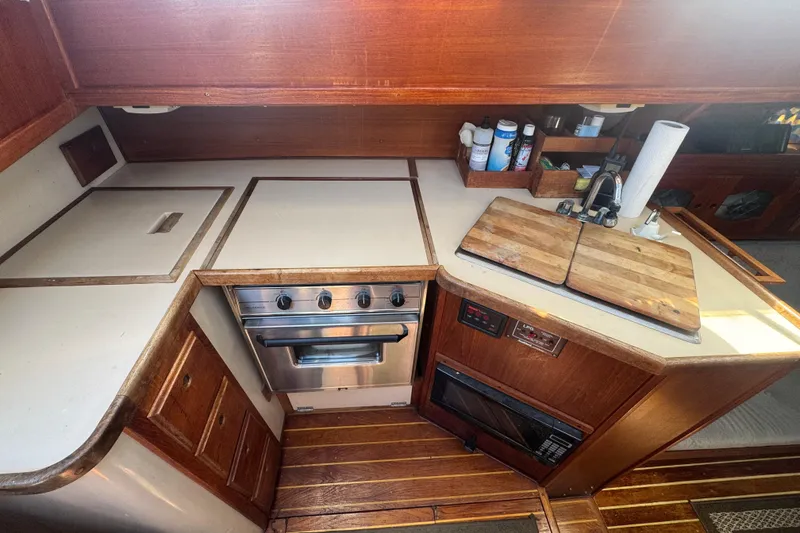 1988 Gulf Pilot House kitchen with stove, wooden cabinets, and cutting boards.