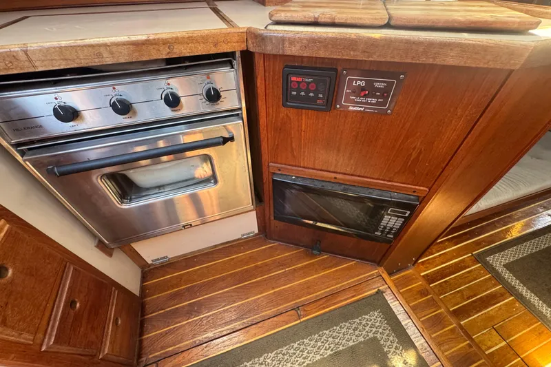 1988 Gulf Pilot House kitchen with stove, microwave, and wooden cabinetry.