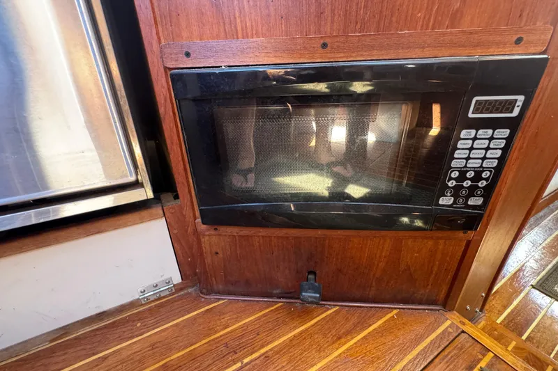 Microwave in 1988 Gulf Pilot House boat kitchen with wooden cabinetry.