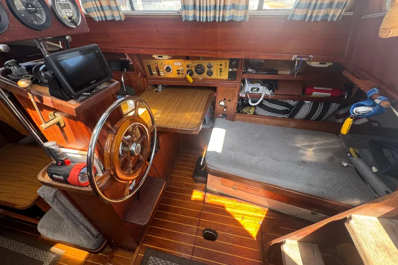 1988 Gulf Pilot House interior with wooden helm, navigation equipment, and cozy seating area.