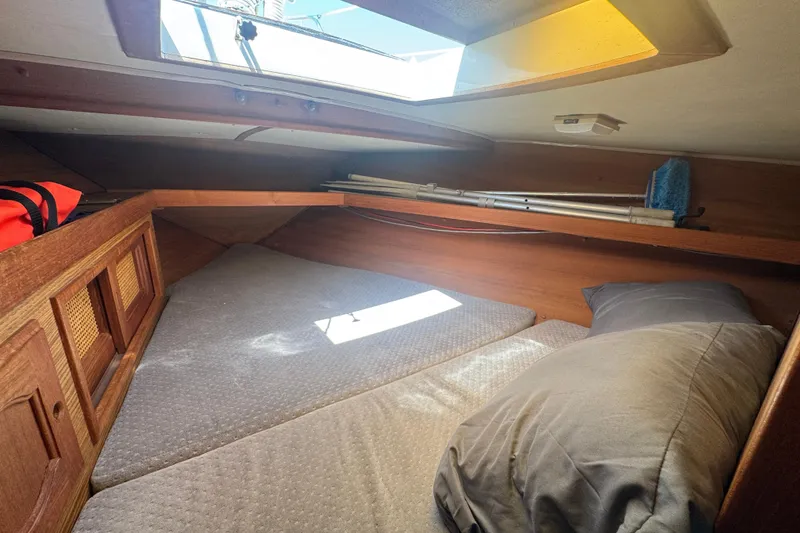 Cozy cabin interior of 1988 Gulf Pilot House boat with bedding and storage.