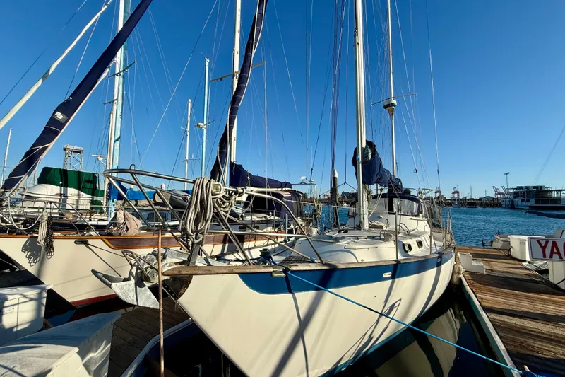 Sailboat docked at marina, Mariner Mayflower 1981, under clear blue sky.