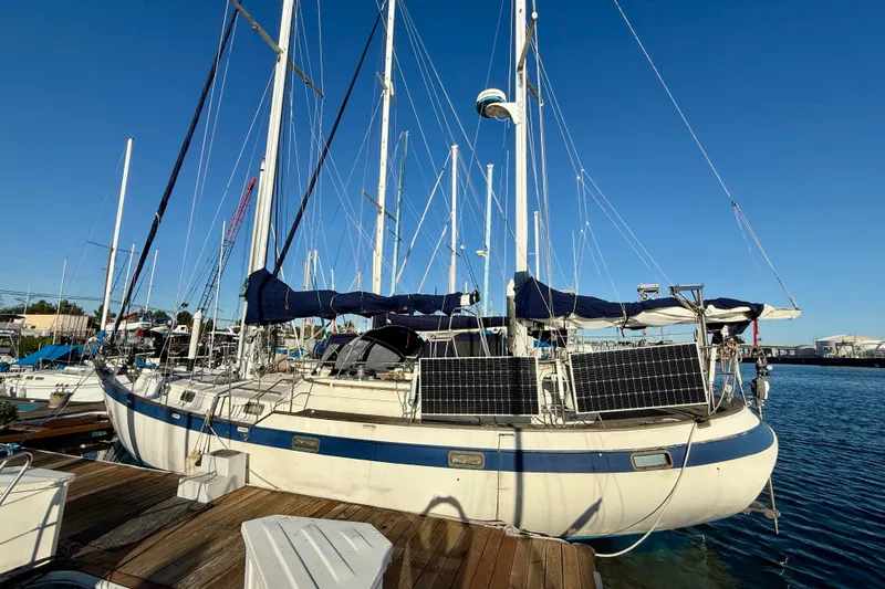 Sailboat docked at marina, Mariner Mayflower 1981, equipped with solar panels.