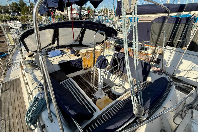 1981 Mariner Mayflower sailboat cockpit with steering wheel, ropes, and seating at marina.