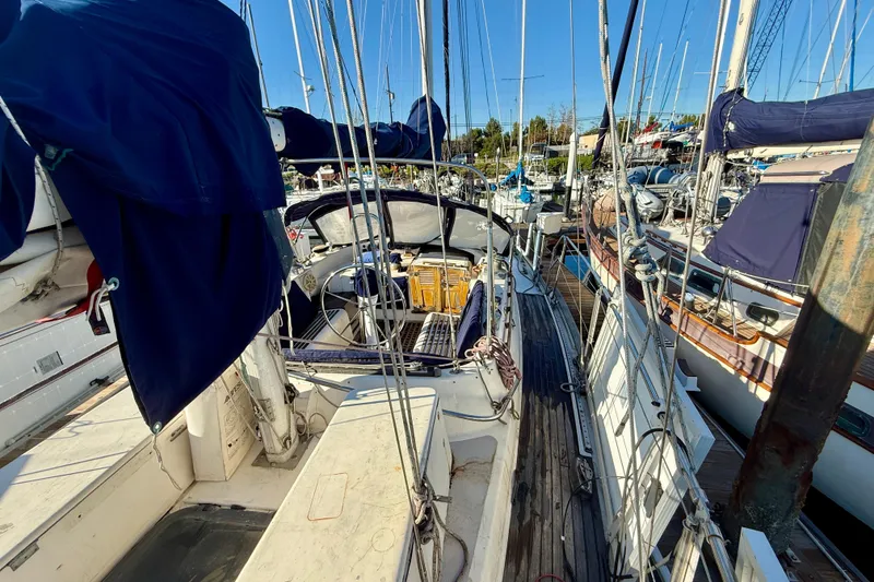 1981 Mariner Mayflower sailboat docked at marina, featuring blue covers and wooden deck.
